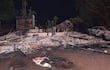 Sitio del Puesto Policial N° 4 en Naranjito, con estructuras colapsadas y un vehículo parcialmente quemado en la noche.