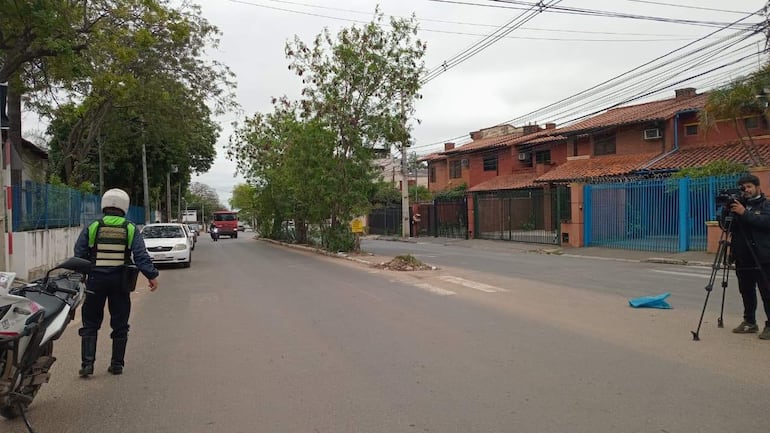 Agente de tránsito en chaleco y casco regulando el tráfico, camarógrafo grabando en un barrio tranquilo de Asunción.