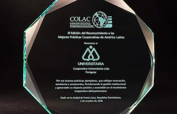 Trofeo octagonal de cristal, en reconocimiento a la Cooperativa Universitaria Ltda de Paraguay, sobre soporte transparente en fondo neutro.