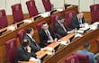 Carlos Núñez Aguero y Mario Alberto Varela Cardozo conversan sentados en un recinto legislativo con sillas rojas.