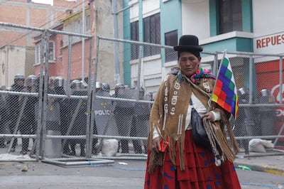 Una mujer campesina afín al expresidente Evo Morales camina frente a policías durante unos enfrentamientos, en el centro de La Paz (Bolivia).
