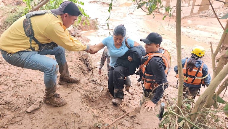 Una mujer recibe ayuda tras el desbordamiento de un río este sábado, en El Torno (Bolivia).