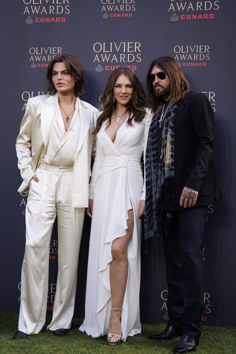 La diosa Liz Hurley escoltada por Damian Hurley y Billy Ray Cyrus en los Olivier Awards 2026. (EFE/EPA/TOLGA AKMEN)
