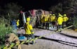 Rescatistas en uniformes amarillos rodean un camión volcado en la maleza, organizándose para ayudar en la escena del accidente.