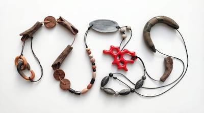 Collares de madera, cerámica y cuentas de colores sobre fondo blanco, mostrando formas abstractas y naturales.