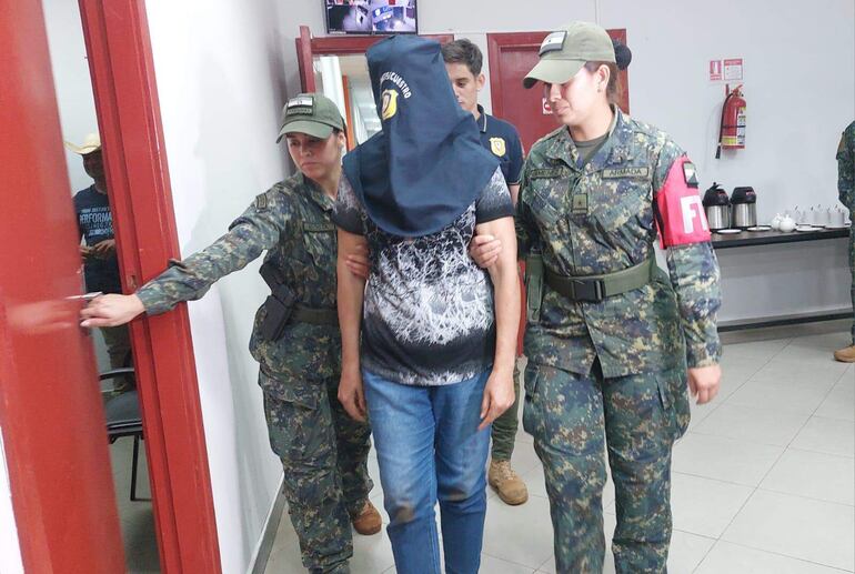 Fotografía cedida por el Ministerio de Defensa de Paraguay de militares custodiando a una presunta integrante de la guerrilla del Ejército del Mariscal López (EML).