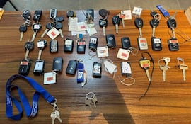 Colección de llaves y controles remotos sobre superficie de madera, sin personas visibles en el ambiente interior.