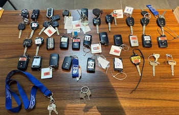 Colección de llaves y controles remotos sobre superficie de madera, sin personas visibles en el ambiente interior.