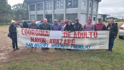 Grupo de adultos mayores de Arazapé sosteniendo un cartel, todos con ropa de abrigo y expresiones de felicidad y tranquilidad.