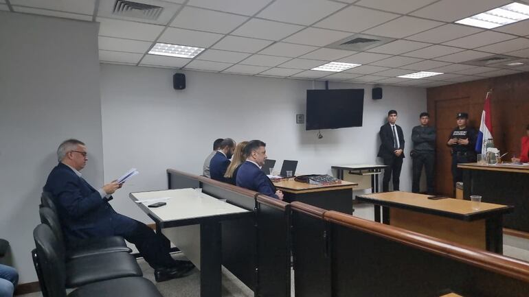 El exsenador argentino Edgardo Kueider sentado en el banquillo de los acusados, junto con Iara Guinsel y sus abogados defensores.