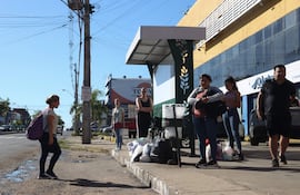 Personas esperan autobuses de servicio público en una parada, ante la medida de fuerza iniciada ayer.