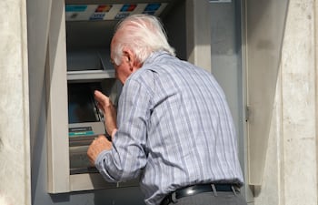 Un jubilado retira dinero de un cajero automático.