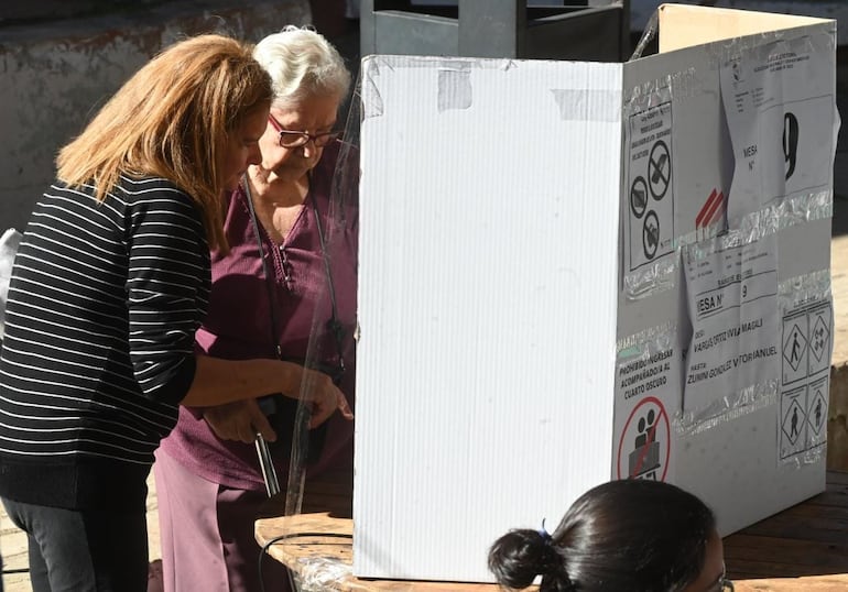 Adulta mayor siendo asistida para ejercer su voto.