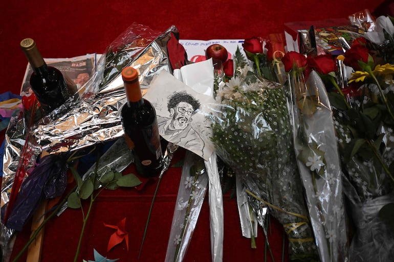 Flores y botellas de vino son depositados en honor a Rubén Rada durante el funeral que se lleva a cabo en el Palacio Legislativo de Montevideo.