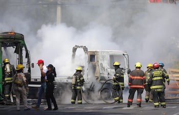 Integrantes del Cuerpo de Bomberos de Guadalajara intentan apagar un vehículo incendiado este domingo, en Guadalajara (México). El líder del Cartel de Jalisco Nueva Generación (CJNG), Nemesio Oseguera Cervantes, alias El Mencho, uno de los capos más buscados por EE.UU., fue abatido durante un operativo con fuerzas federales.