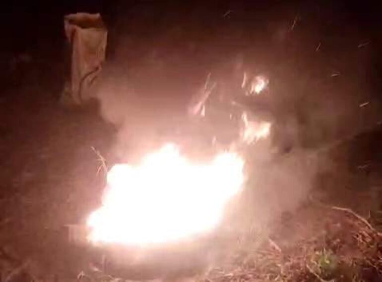 Fuego intenso ardiendo en la noche, generando humo, en un entorno rural sin personas visibles.