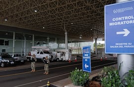 Dos agentes de seguridad armados con uniformes camuflados vigilan un control migratorio en un entorno ordenado.