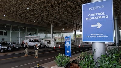 Dos agentes de seguridad armados con uniformes camuflados vigilan un control migratorio en un entorno ordenado.