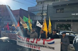 Grupo de jubilados con banderas amarillas, verdes y rojas, mostrando un banner de la Unión Nacional de Jubilados en un ambiente exterior.