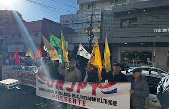 Grupo de jubilados con banderas amarillas, verdes y rojas, mostrando un banner de la Unión Nacional de Jubilados en un ambiente exterior.
