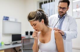 Una paciente que sufrió de neumonía está tosiendo y el médico escucha el sibileo en los pulmones con un estetoscopio. Imagen ilustrativa.
