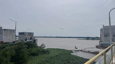 Paisaje natural con río marrón y estructuras industriales para tratamiento de agua, sin presencia humana.