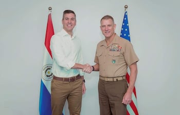 El Gral. Donovan en uniforme militar con medallas, estrecha la mano de un hombre con camisa clara y pantalones marrones, en un ambiente institucional.