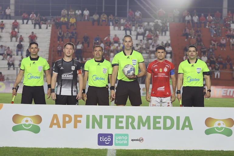 Los protagonistas, capitanes de ambos elencos, el árbitro y sus asistentes, antes del comienzo del partido.