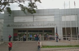 Cinco personas en la entrada del moderno Centro de Atención Ambulatoria, algunas conversan y otras esperan pacientemente.