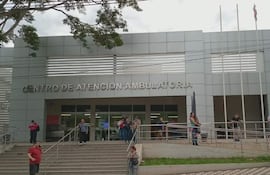 Cinco personas en la entrada del moderno Centro de Atención Ambulatoria, algunas conversan y otras esperan pacientemente.