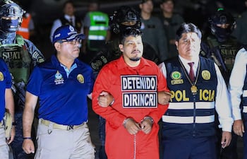 Policías peruanos escoltan a Erick Moreno Hernández (C), conocido como "El Monstruo", quien llega tras ser extraditado desde Paraguay a la Dirección de Aviación Policial (DIRAVPOL) en Collao, Perú.