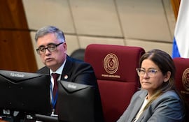 Miguel Báez Reyes, hombre canoso con traje oscuro, habla en el Legislativo. Mujer con chaqueta gris escucha atentamente.