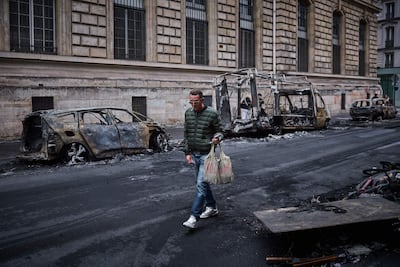 Un hombre pasa junto a una hilera de vehículos calcinados en la Rue Yves Toudic, destruidos tras una protesta a escala nacional contra el «alto costo de la vida» en el centro de París, el 19 de octubre de 2026.