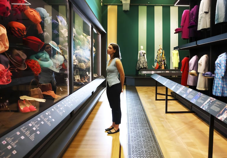 Una empleada de la galería observa los sombreros usados ​​por la reina Isabel II de Gran Bretaña, que se exhiben en la exposición La reina Isabel II: Su vida con estilo. (EFE/EPA/NEIL HALL)
