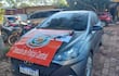 Automóvil gris estacionado en área policial con documentos sobre el techo, incluyendo 'EVIDENCIA' y letrero de 'Dirección de Policía Central'.
