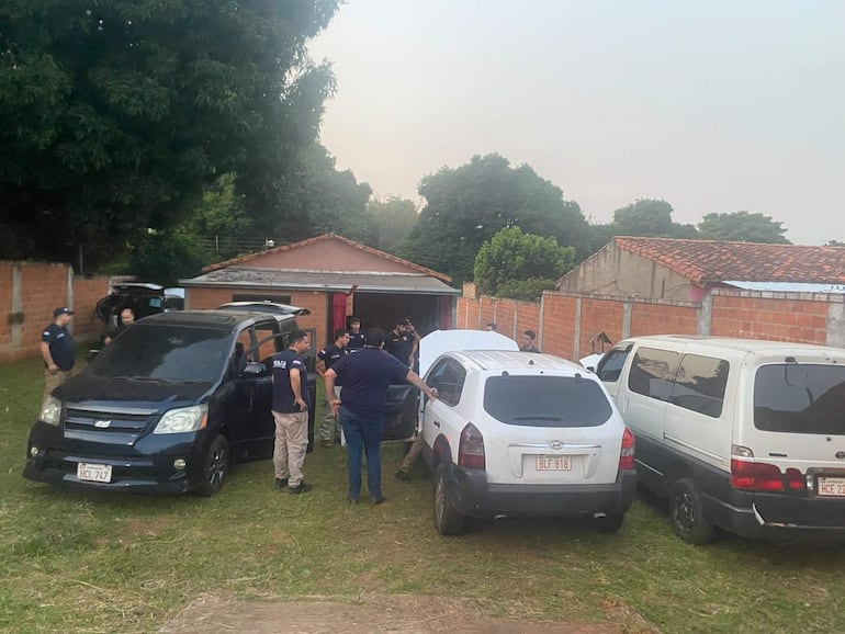Grupo de personas vestidas con camisetas oscuras y pantalones claros, revisando vehículos en zona rural.