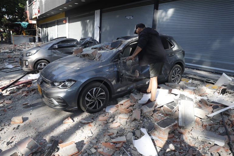 Un hombre observa un vehículo afectado tras un fuerte temblor este lunes, en Cali (Colombia).