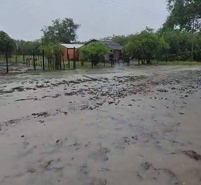 Paisaje inundado en área rural, con casas de chapa y madera rodeadas de agua estancada y lodo.