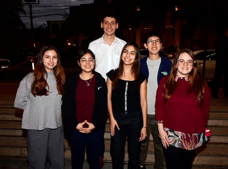 Grupo de seis jóvenes sonrientes posando al aire libre en Asunción, vestidos casualmente con prendas de abrigo y ligeras.