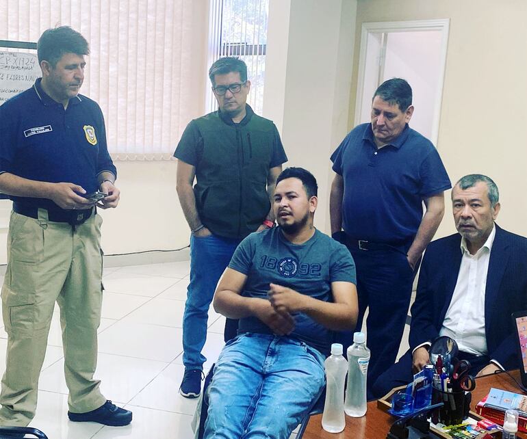 Sentado, con remera, Edgar Ayala, quien denunció a los policías por extorsión y otros delitos, pero luego dijo que solo fueron a "dar una vuelta". Atrás, lo observa el fiscal Federico Delfino.