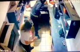 Momento en que uno de los asaltantes busca el dinero en la caja.