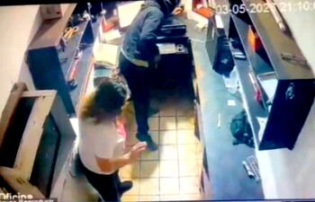 Momento en que uno de los asaltantes busca el dinero en la caja.