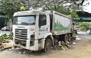 Camión de basura municipal DIESA estacionado entre montones de residuos en un entorno urbano sin personas presentes.