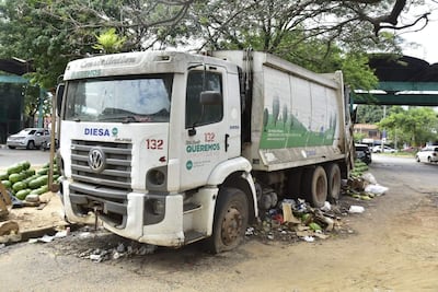 Camión de basura municipal DIESA estacionado entre montones de residuos en un entorno urbano sin personas presentes.