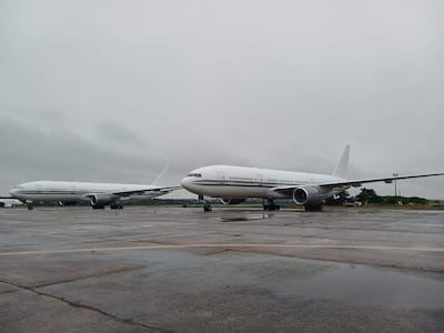 Dos aviones Boeing 767 blancos en un aeropuerto con cielo nublado y pavimento húmedo, sin personas visibles.