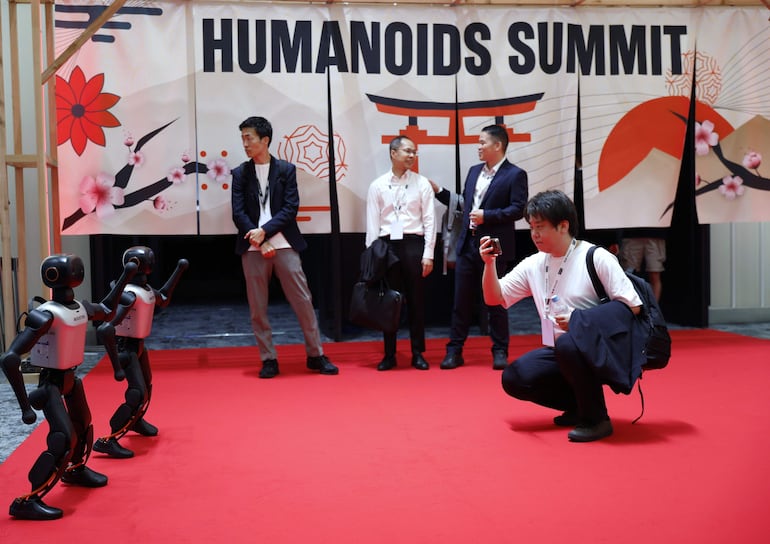 Un visitante fotografía a los robots Booster K1 mientras realizan una coreografía durante la Humanoids Summit en Tokio, Japón, el 28 de mayo de 2026.