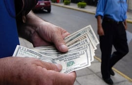 Imagen ilustrativa: un cambista muestra billetes de dólares americanos.
