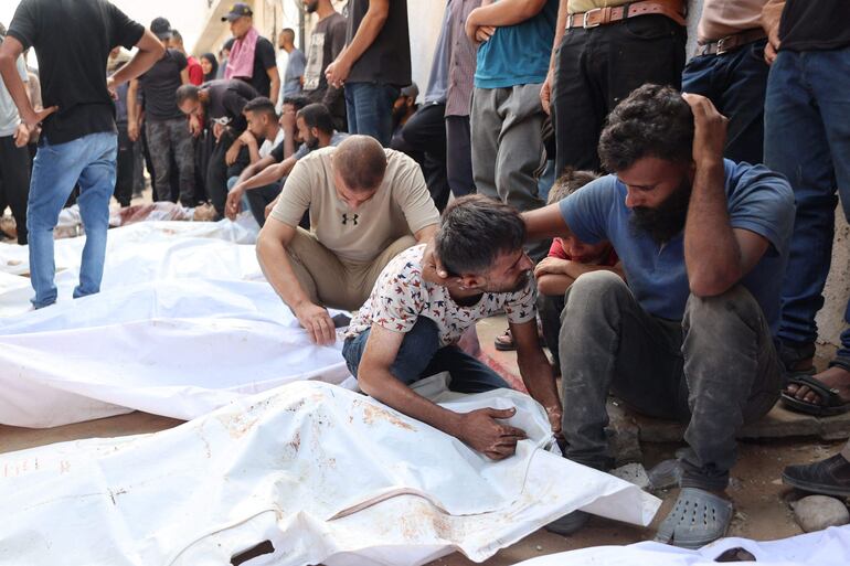 Varias personas lloran junto a los cuerpos de familiares fallecidos a causa de bombardeos israelíes, este jueves en el hospital Al Shifa en la Ciudad de Gaza.