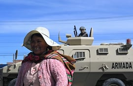 Una mujer sonríe cerca de un vehículo blindado militar en una zona de bloqueo en Cruce Ventilla, El Alto, Bolivia, el 20 de junio de 2026, luego de que el presidente boliviano Rodrigo Paz declarara el estado de emergencia.