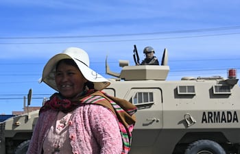 Una mujer sonríe cerca de un vehículo blindado militar en una zona de bloqueo en Cruce Ventilla, El Alto, Bolivia, el 20 de junio de 2026, luego de que el presidente boliviano Rodrigo Paz declarara el estado de emergencia.